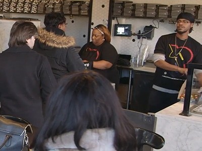 A group of people standing at an &pizza counter in a restaurant.
