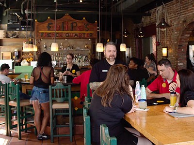 Employee serving customers at Felipes Taqueria restaurant.