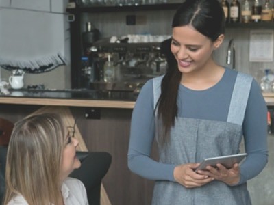 Woman serving people in restaurant using a tablet as POS system.