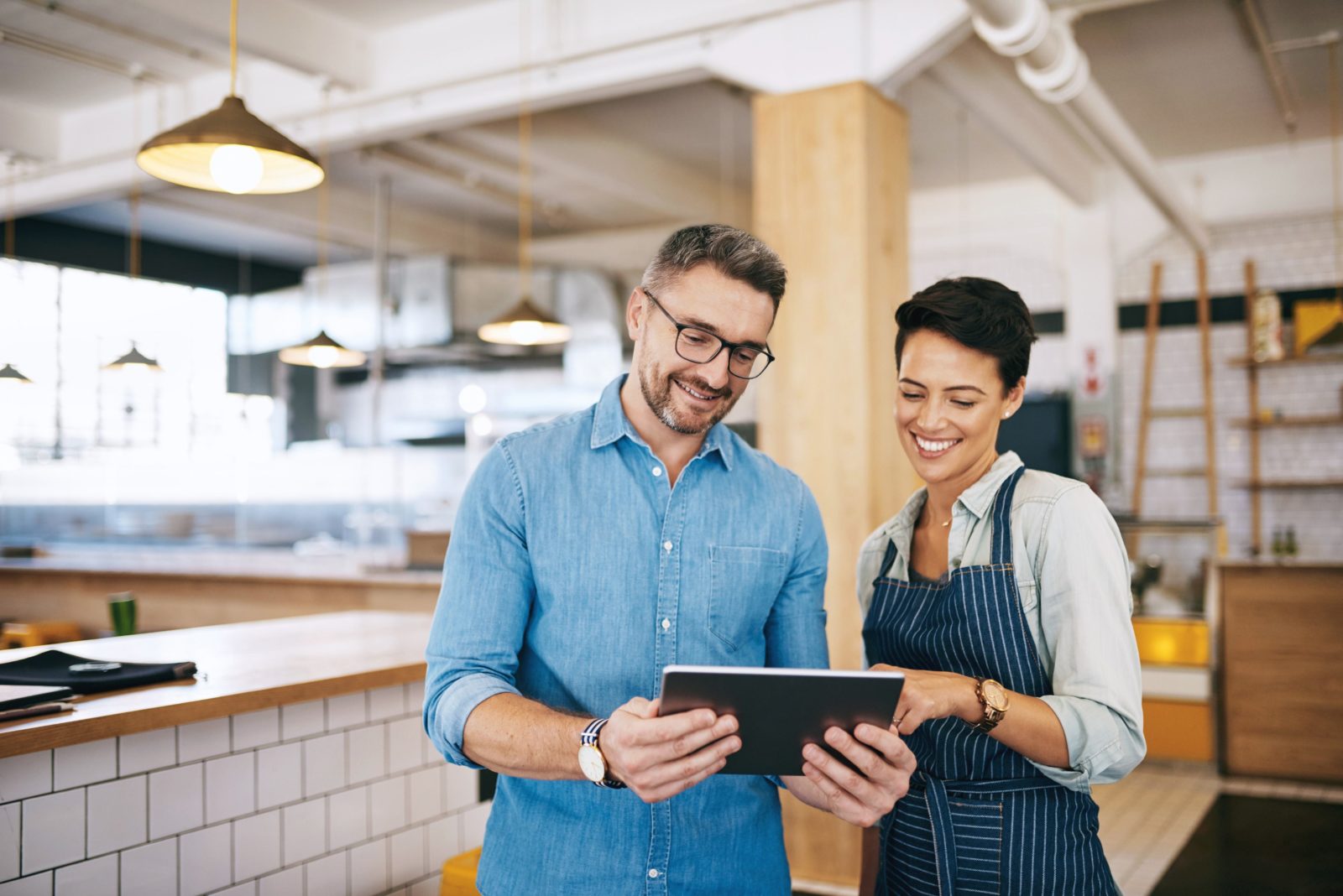 Male and female sales people in kitchen studio looking at tablet together