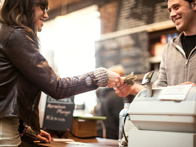 A man and woman are shaking hands at a cash register.