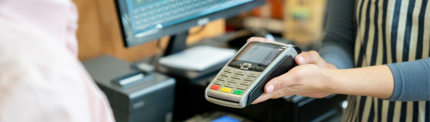 Employee helping a customer pay by handing them the POS system.