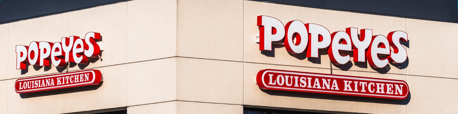 popeyes-testimonial-thin-banner A sign for popeye's on the side of a building.