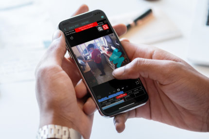 A person holding a smartphone with a video on it.