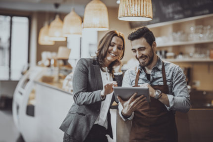 Two business people looking at a tablet in a coffee shop.