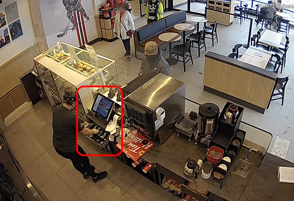 A man is standing at the counter of a coffee shop.