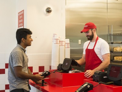 Two men standing at a counter in a fast food restaurant.