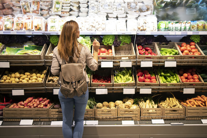 woman-buying groceries A woman looking at vegetables in a grocery store.