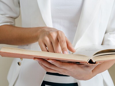 A woman pointing at and reading a book