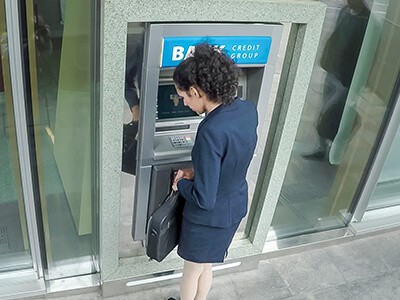 A woman is standing in front of an atm machine.