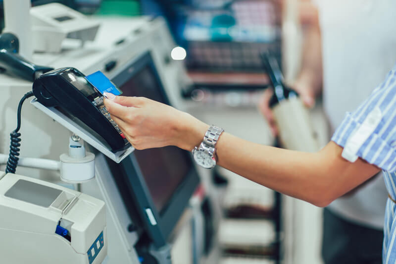 A woman paying at the self checkout at a grocery store