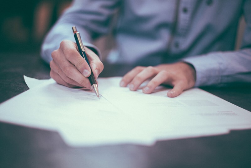 A closeup of a man signing a document