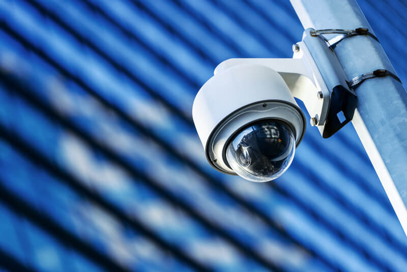 A dome surveillance camera on a metal pole