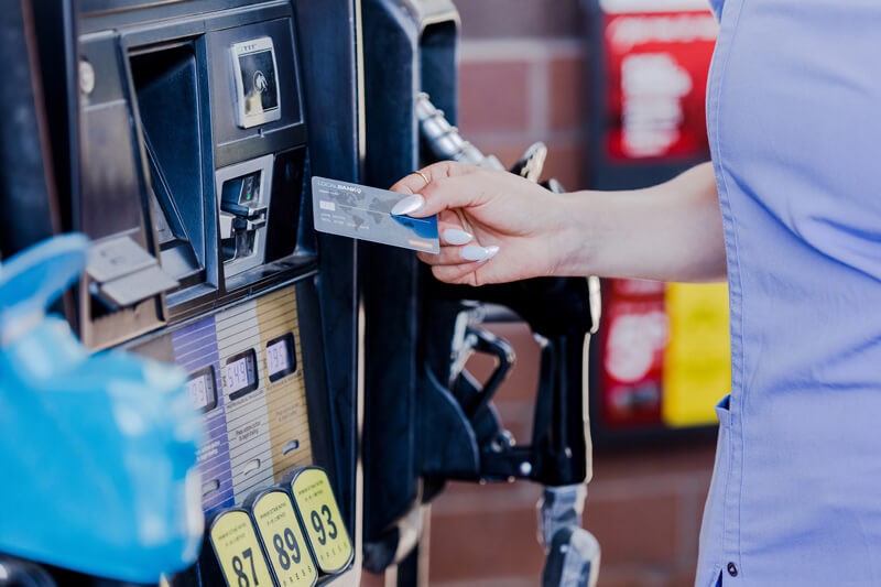A woman paying for gas at the pump at a gas station