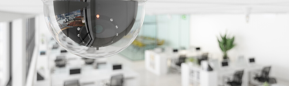 A cctv camera hanging from the ceiling of an office.