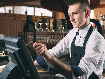 A man at a bar using a credit card machine.