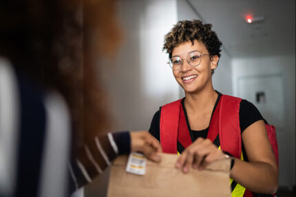 A woman handing a package to another woman.