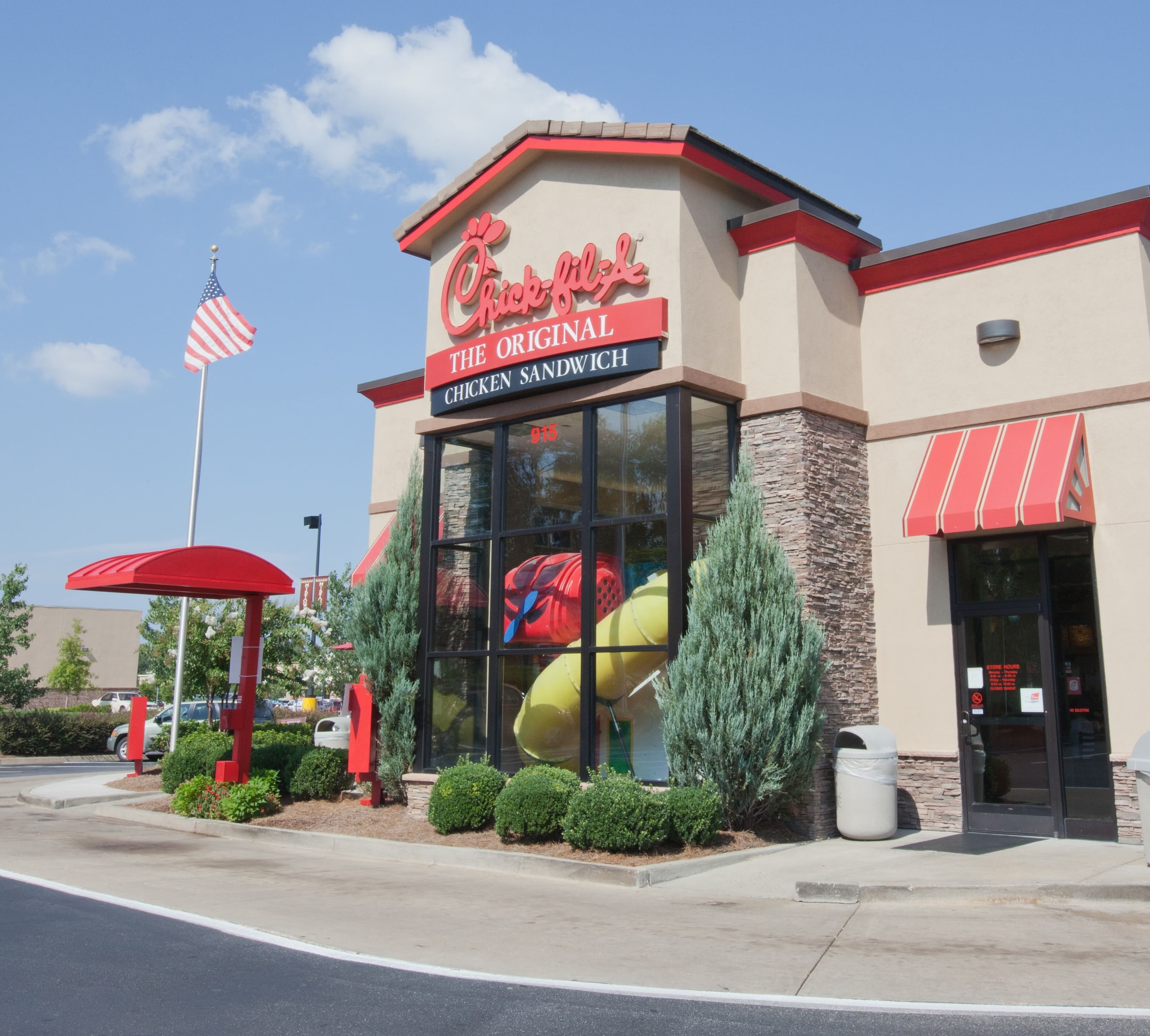 Exterior of a Chick-fil-A restaurant with a drive-thru and outdoor signage, including an American flag.