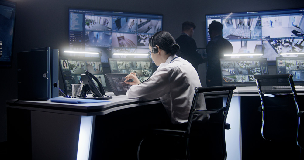 A man is sitting at a desk with several monitors in front of him.