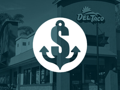 Exterior of a Del Taco restaurant with a dollar sign and anchor symbol overlay.