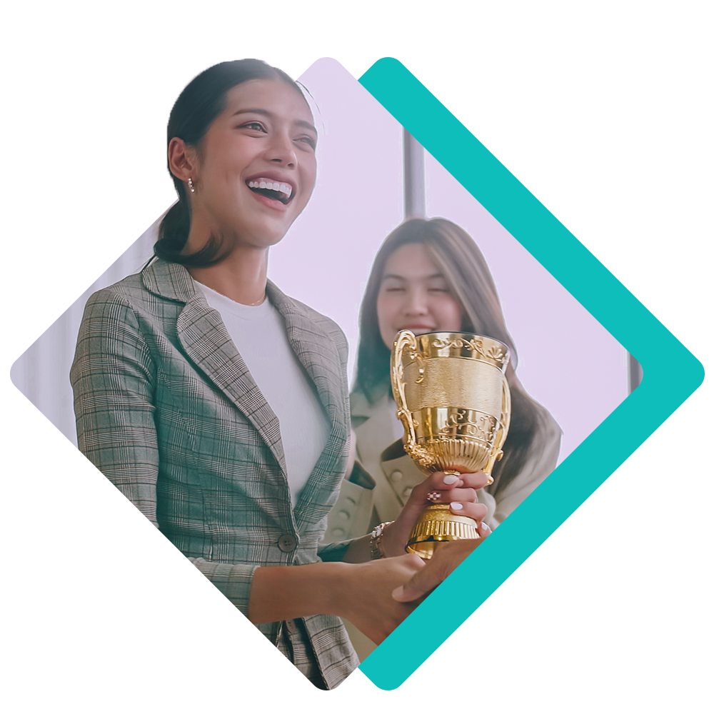 Two people smiling, one holding a gold trophy in a checkered blazer.