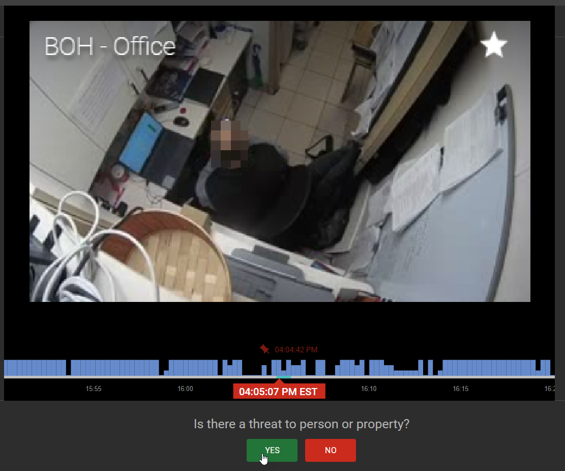Snag_316bcb6f Security camera view of a small office with a person sitting at a desk, surrounded by papers and office equipment. A prompt at the bottom asks if there is a threat to person or property.
