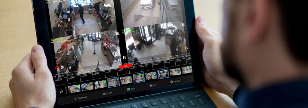 Person viewing multiple security camera feeds on a tablet screen.