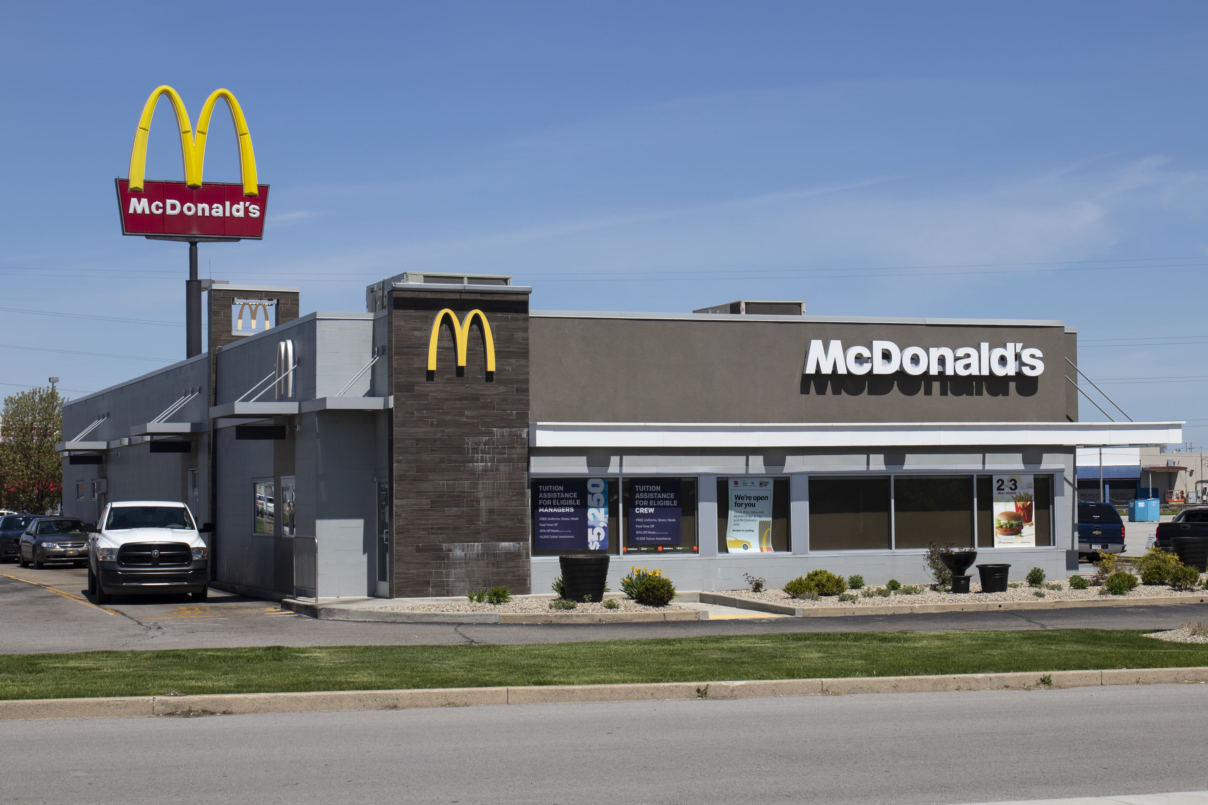 Exterior view of a McDonald's restaurant with a red and yellow sign. A white truck is parked nearby.