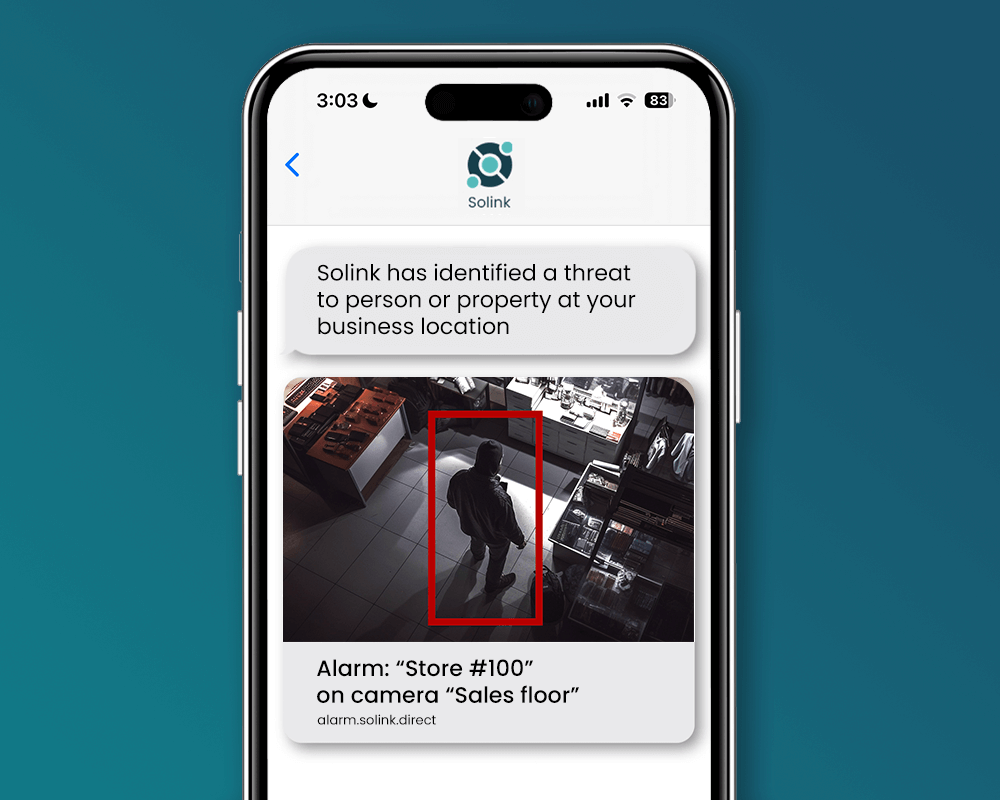 Smartphone screen displaying a security alert message from Solink, with an image of a person in a store's sales floor highlighted by a red box.