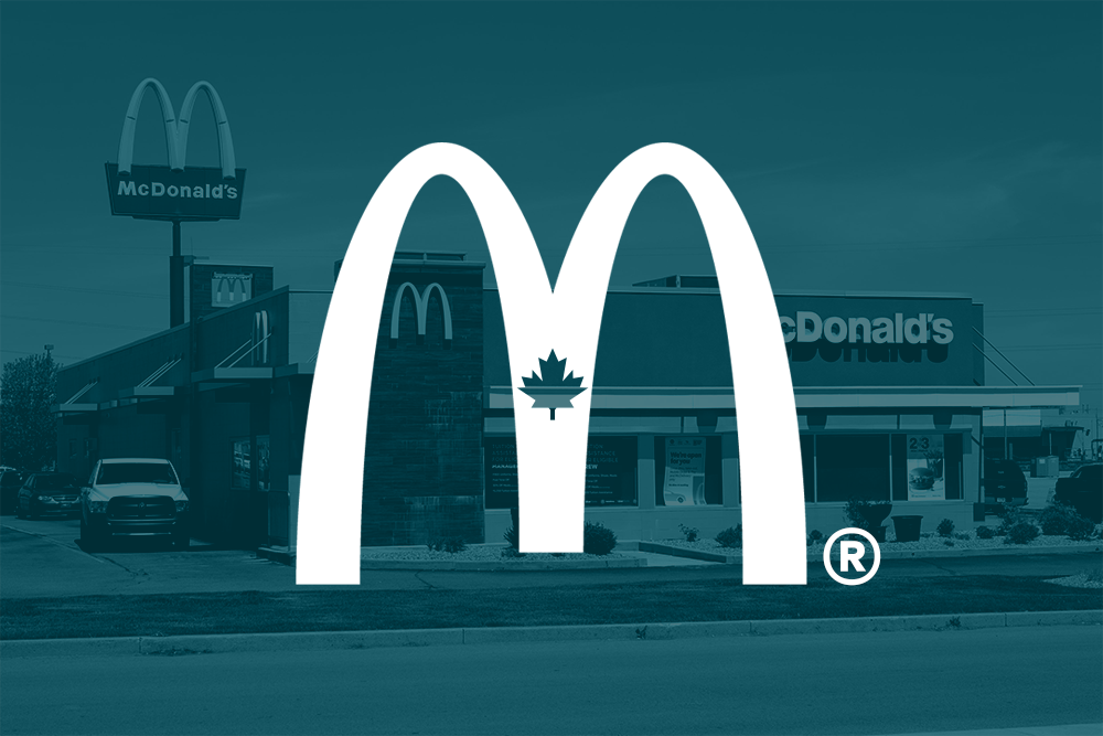 A McDonald's restaurant exterior with a large M logo featuring a maple leaf in the center, indicating a Canadian location.