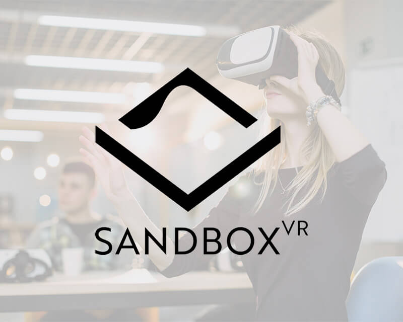 Person wearing a VR headset with the Sandbox VR logo overlay.