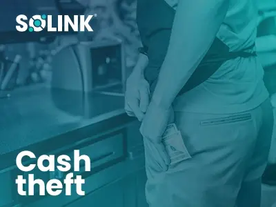 Person discreetly placing cash into their pocket near a countertop, with the word "Cash theft" and the Solink logo visible.