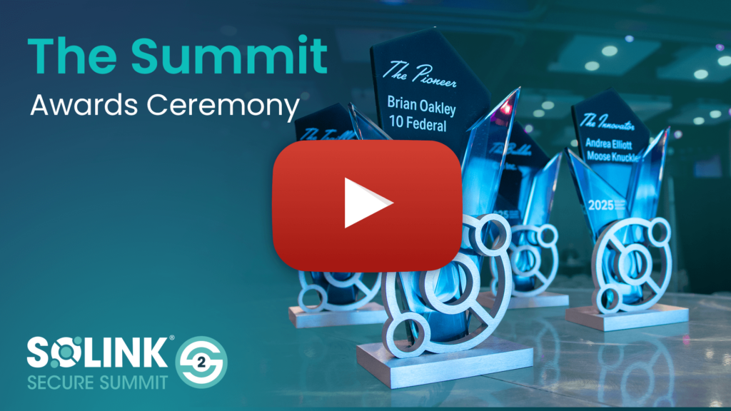 Several glass awards with blue accents are displayed on a table at the Solink Secure Summit Awards Ceremony, with a play button overlay in the center.