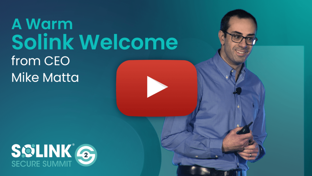 A man in glasses stands on stage holding a remote, with text reading "A Warm Solink Welcome from CEO Mike Matta" and a large play button overlay.