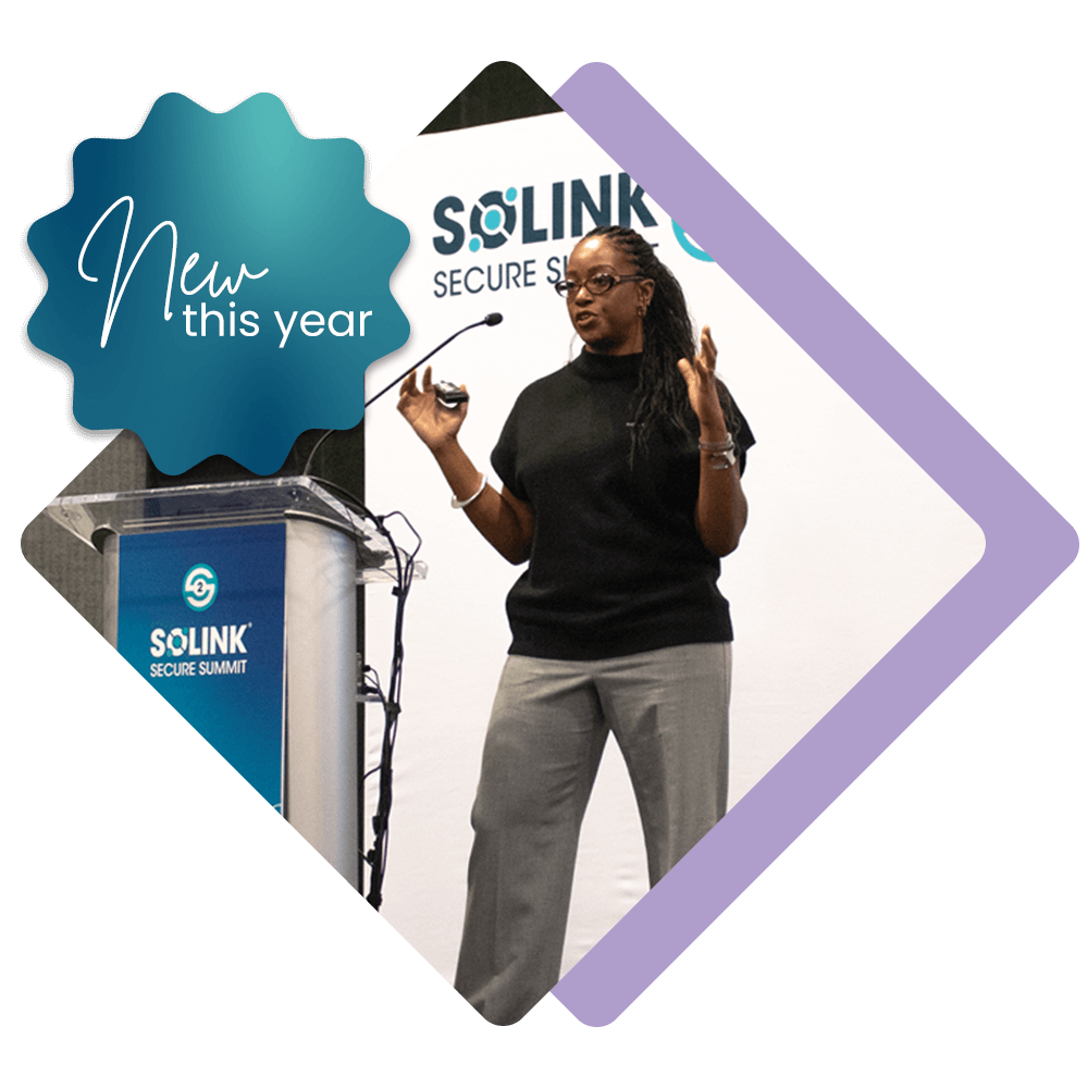 A woman stands on stage giving a presentation at the Solink Secure Summit, holding a remote and gesturing with one hand. A “New this year” badge appears in the corner.