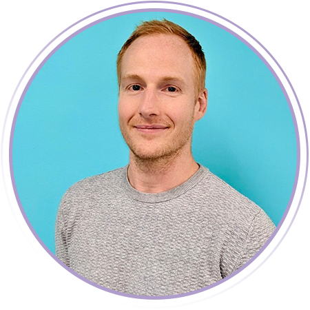 A man with short red hair and a light beard, wearing a light gray textured sweater, stands in front of a turquoise background, framed by a circular graphic border.
