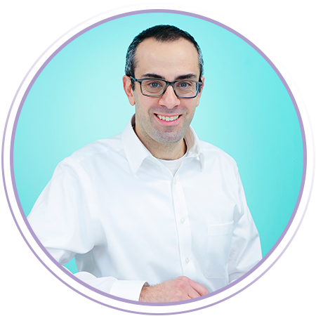 A man wearing glasses and a white button-up shirt smiles at the camera against a light blue background with a purple circular border.