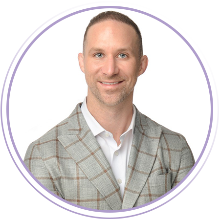 Man wearing a light-colored plaid suit jacket and white shirt, smiling at the camera against a plain white background.