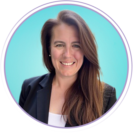 Woman with long brown hair wearing a black blazer and white top, smiling, posed against a light blue background.