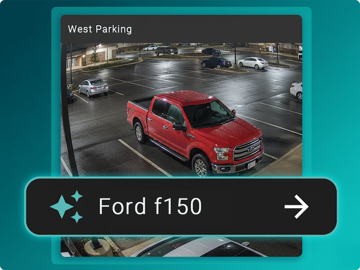 A red Ford F-150 pickup truck is parked in a wet, mostly empty parking lot at night under artificial lights.