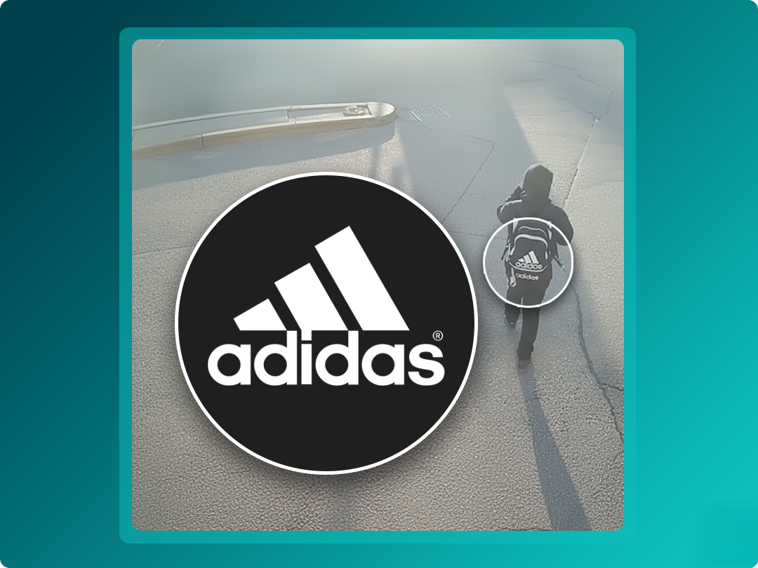 Person walking alone on a paved surface with a backpack, featuring the Adidas logo prominently displayed in the foreground.