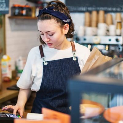 employee-pos-transaction A female barista processing a transaction at a point of sale terminal