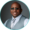 A black man wearing sunglasses and a vest.